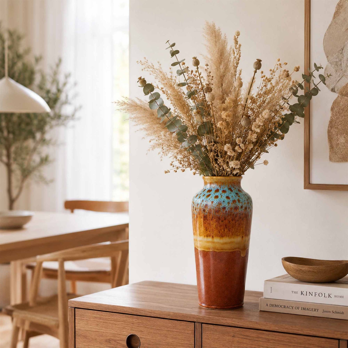 Decorative ceramic vase with dried flowers on a wooden side table in a home setting