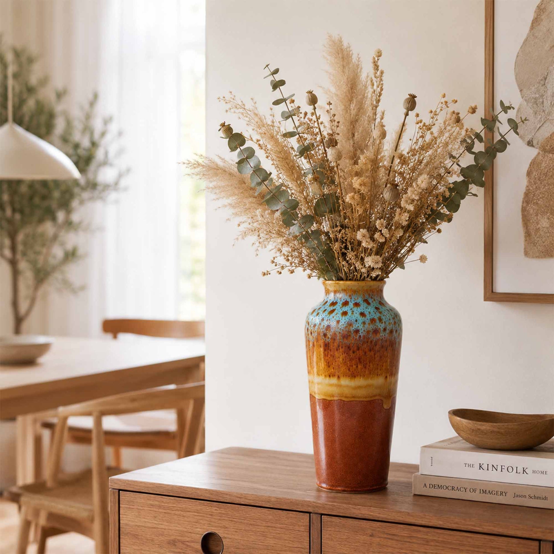 Decorative ceramic vase with dried flowers on a wooden side table in a home setting