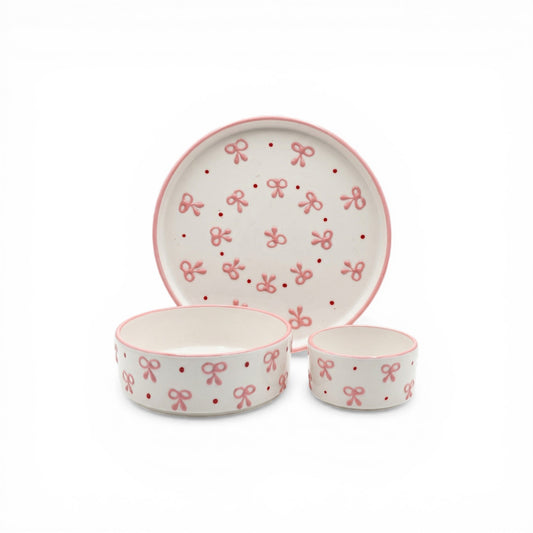 Ceramic bowl and plate set with pink bow pattern on a white background