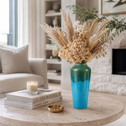 Decorative ceramic vase with dried flowers on a coffee table in a living room.
