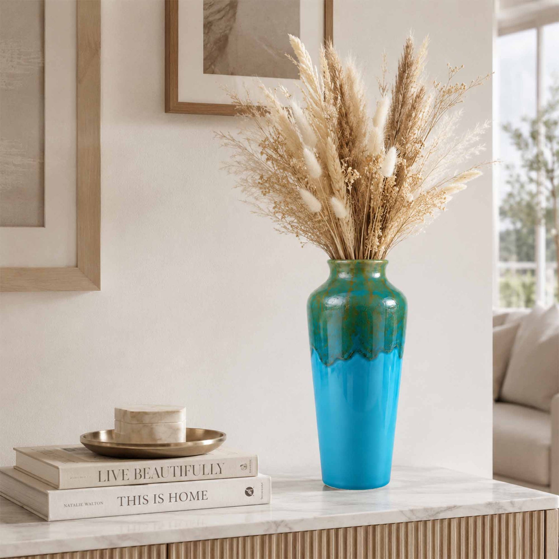 Blue ceramic vase with dried plants on a shelf in a home setting