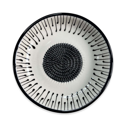 Decorative garlic grater bowl with black spiral design on a white background