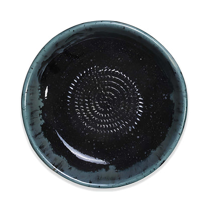 Black ceramic garlic grater bowl with a textured design on a white background