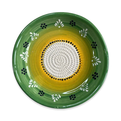 Decorative garlic grater bowl with green rim, yellow center, and white patterns on a white background