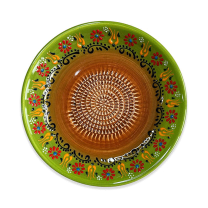 Decorative ceramic garlic grater bowl with green rim and brown center, featuring floral and abstract patterns.