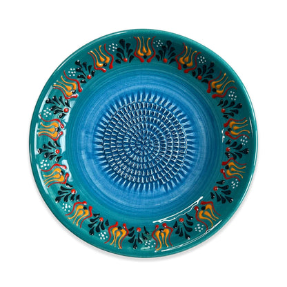 Decorative blue garlic grater bowl with colorful patterns on a white background