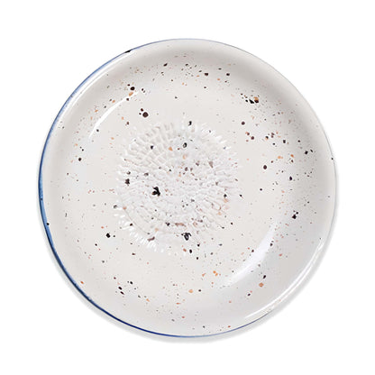Speckled ceramic garlic grater bowl with a blue rim on a white background