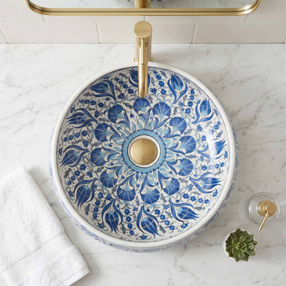 Decorative blue and white floral-patterned sink with gold fixtures on a marble countertop.