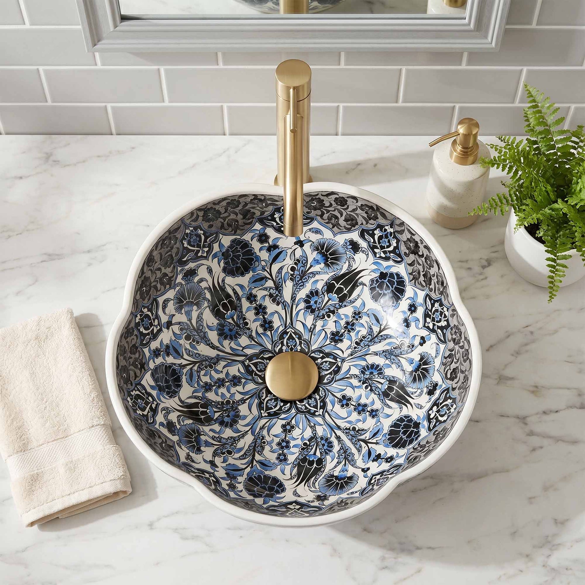 Decorative bathroom sink with floral patterns and gold fixtures on a marble countertop.