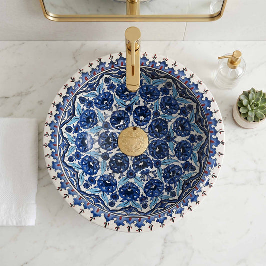 Decorative blue floral-patterned sink with gold faucet on a marble countertop.