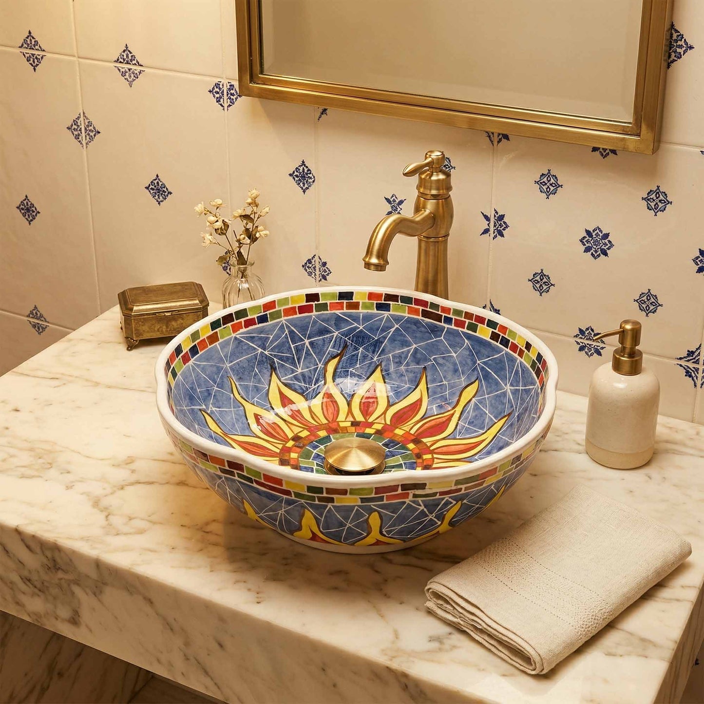 Decorative mosaic sink on a marble countertop with a gold faucet and decorative tiles.