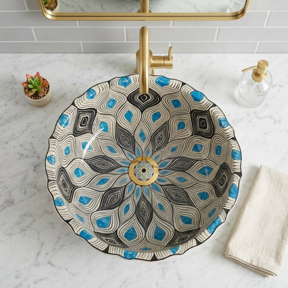 Decorative bathroom sink with blue and black pattern, gold faucet, and white marble countertop.