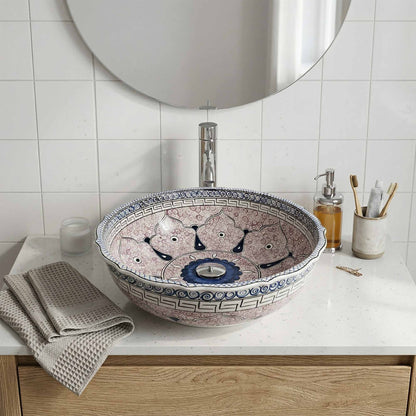 Decorative bathroom ceramic sink with intricate patterns on a white countertop.