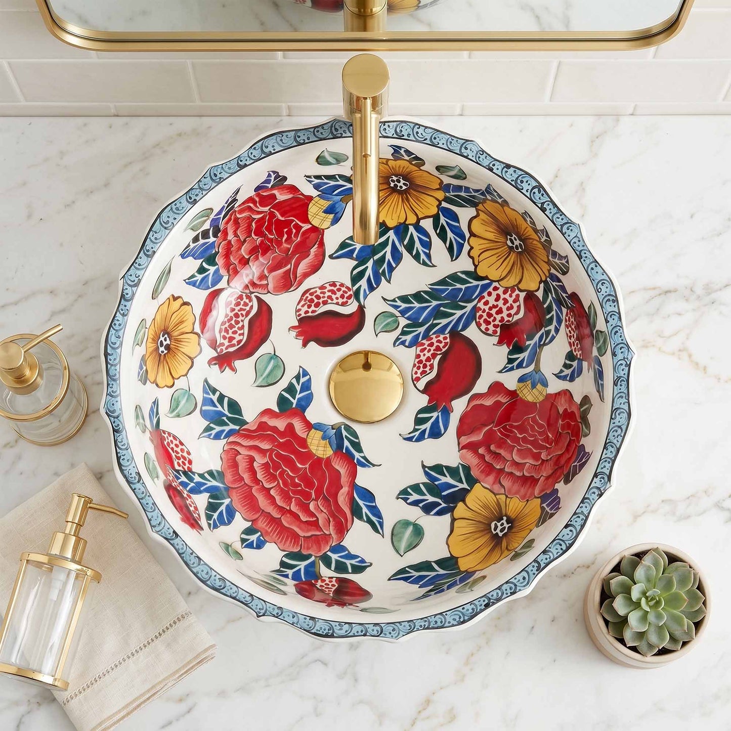 Decorative floral-patterned ceramic sink with gold fixtures on a marble countertop.