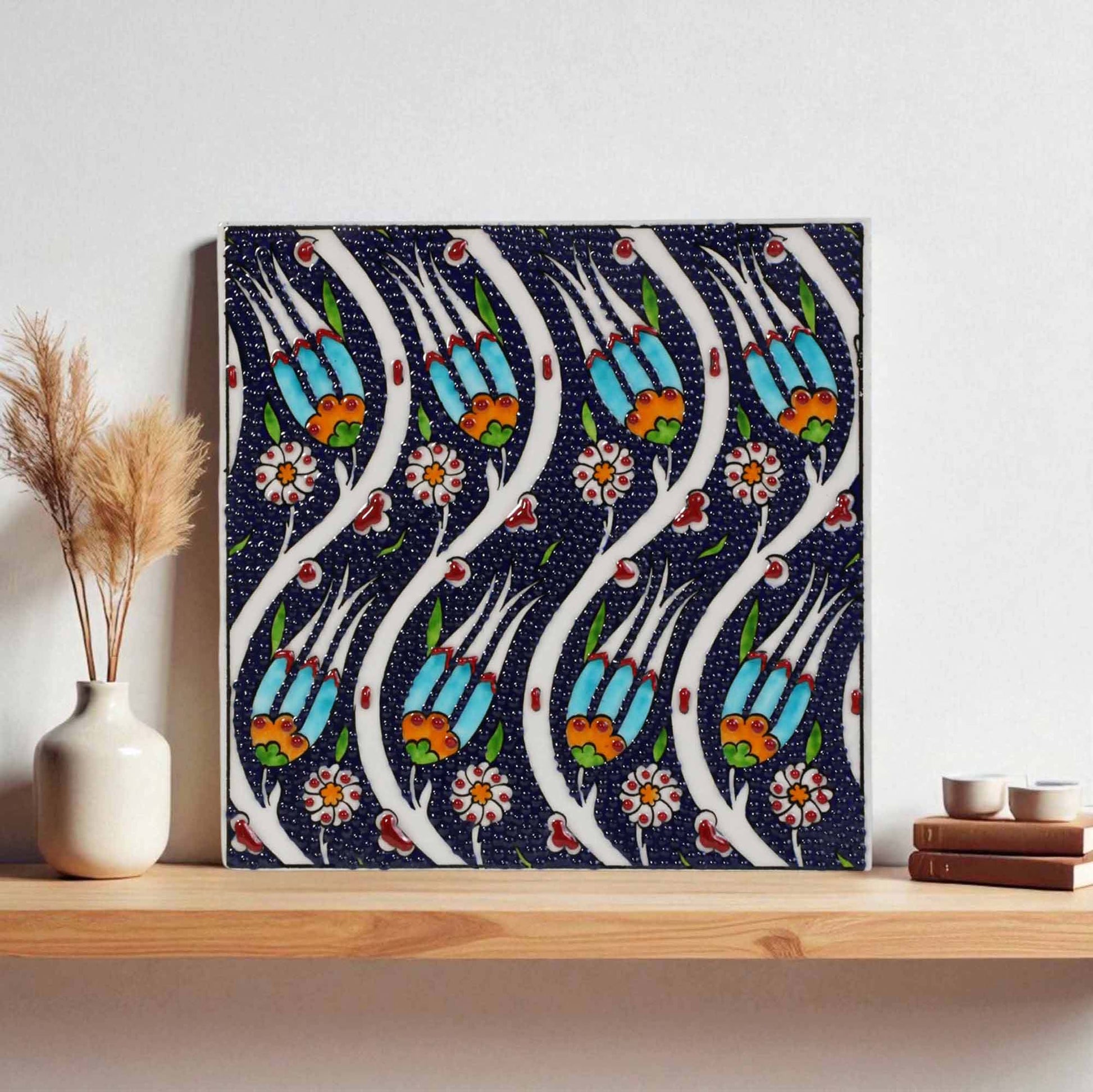 Decorative ceramic tile with floral pattern on a shelf against a white wall