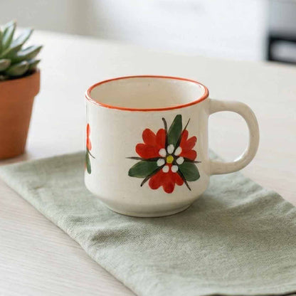 White mug with floral design on a light green cloth, with a blurred background