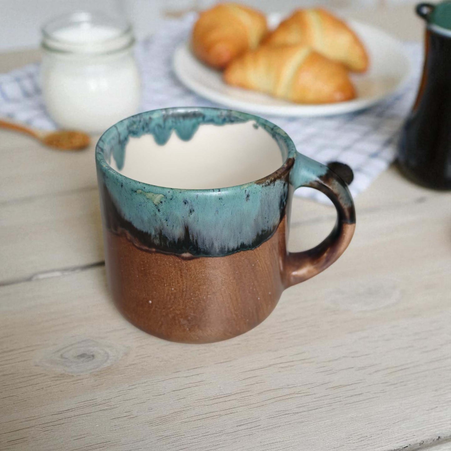 Ceramic mug with blue interior on a wooden table with pastries in the background