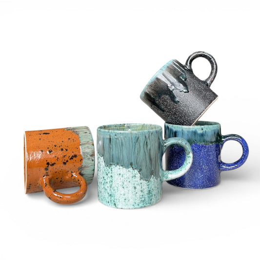 Four ceramic mugs in different colors on a white background