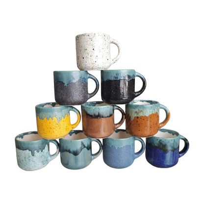 Stack of ceramic mugs with various colors and patterns on a white background
