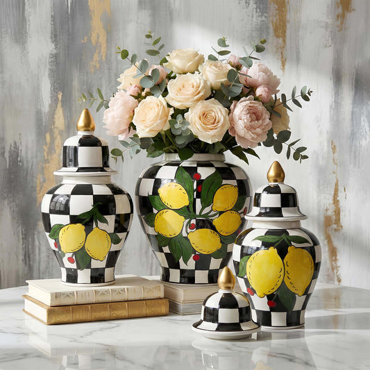 Decorative vases with lemon design on a marble surface with a floral arrangement in the background.