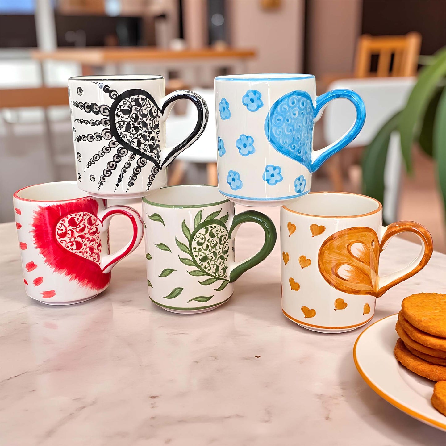 Set of colorful mugs with various designs on a marble surface.