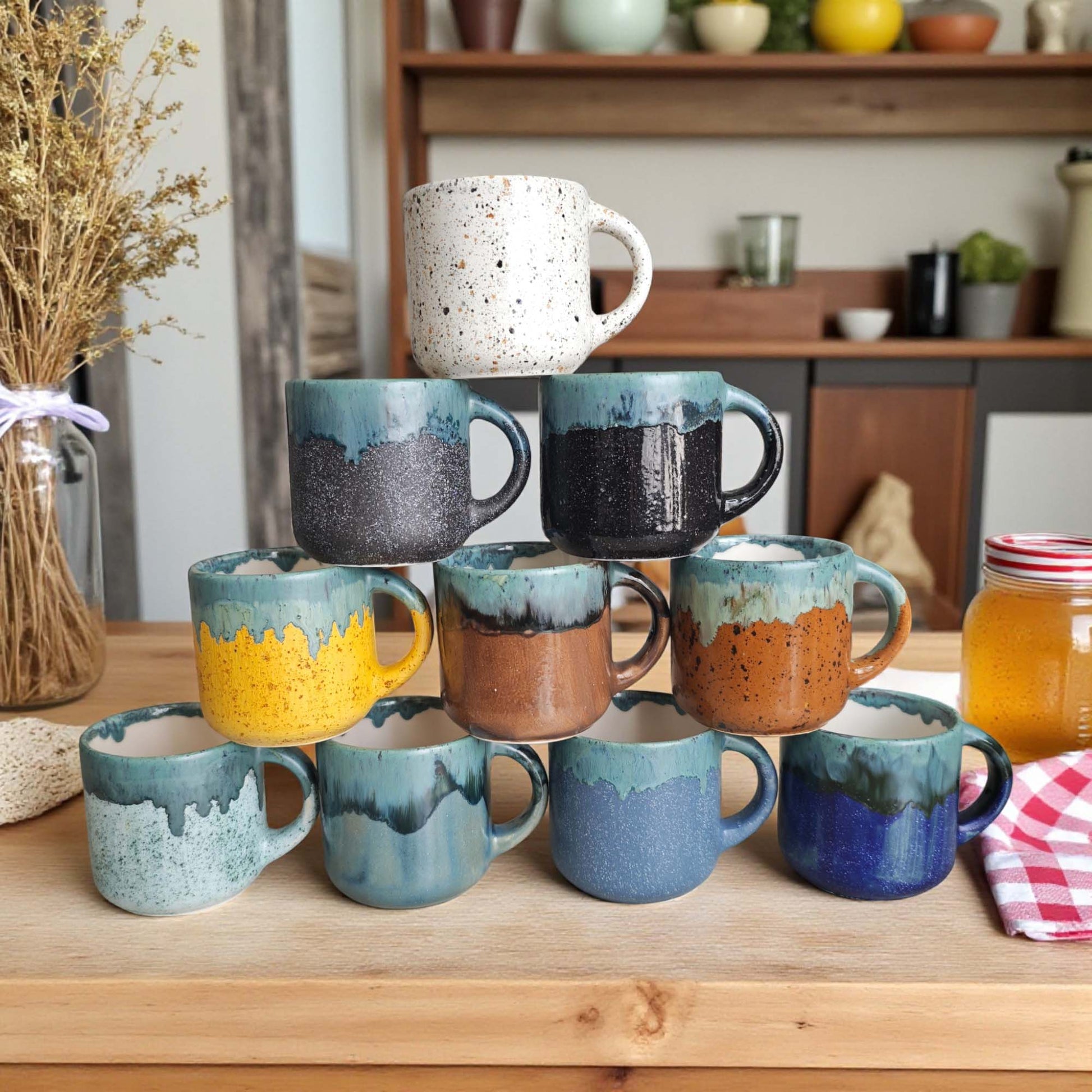 Collection of colorful ceramic mugs on a wooden surface with a kitchen background.