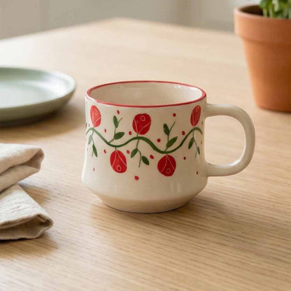 Ceramic mug with red floral design on a wooden table