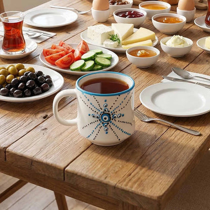 Cup of tea on a wooden table with plates of food including olives, tomatoes, and cheese.