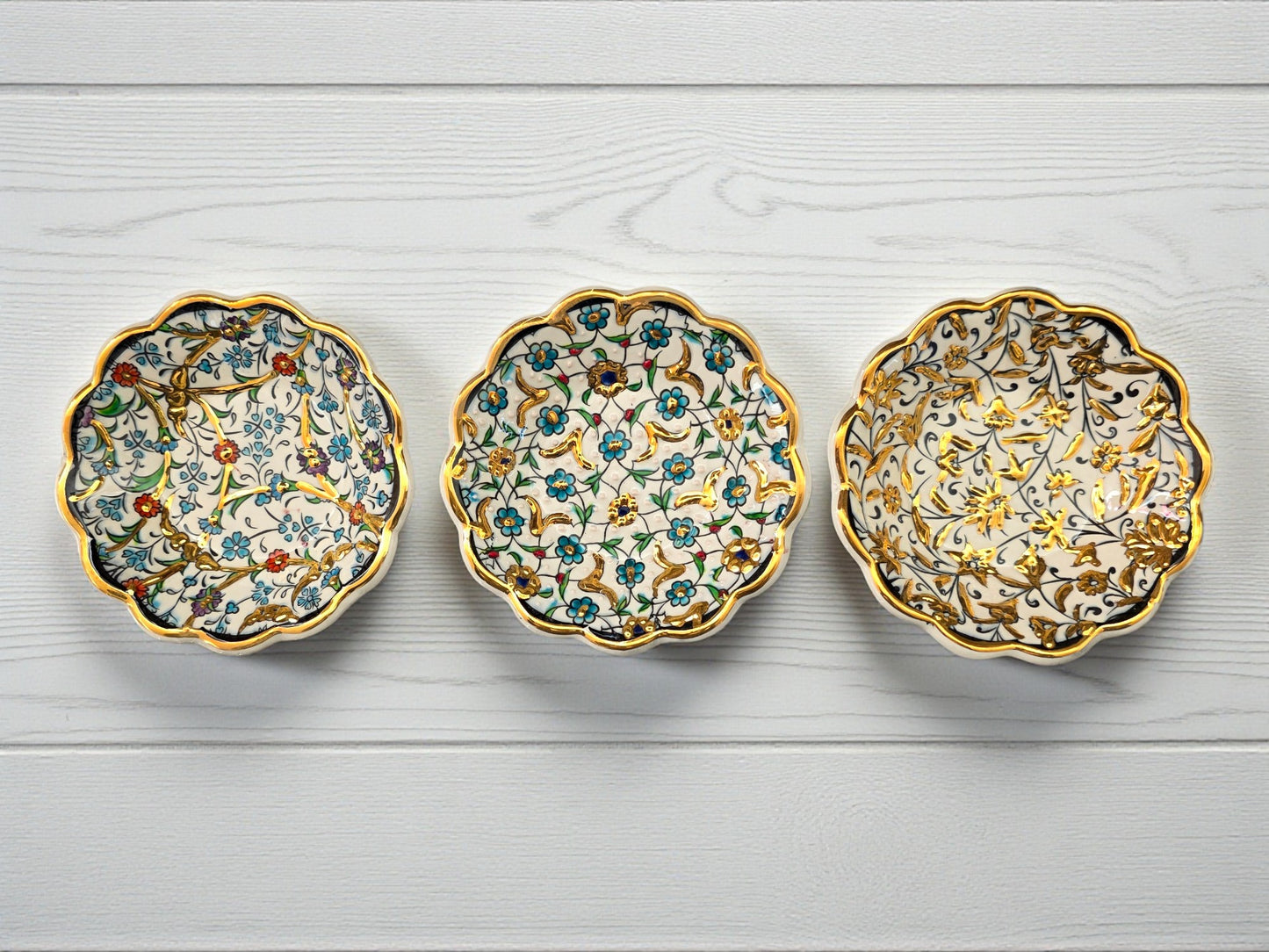 Three decorative ceramic saucers with floral patterns on a light wooden surface