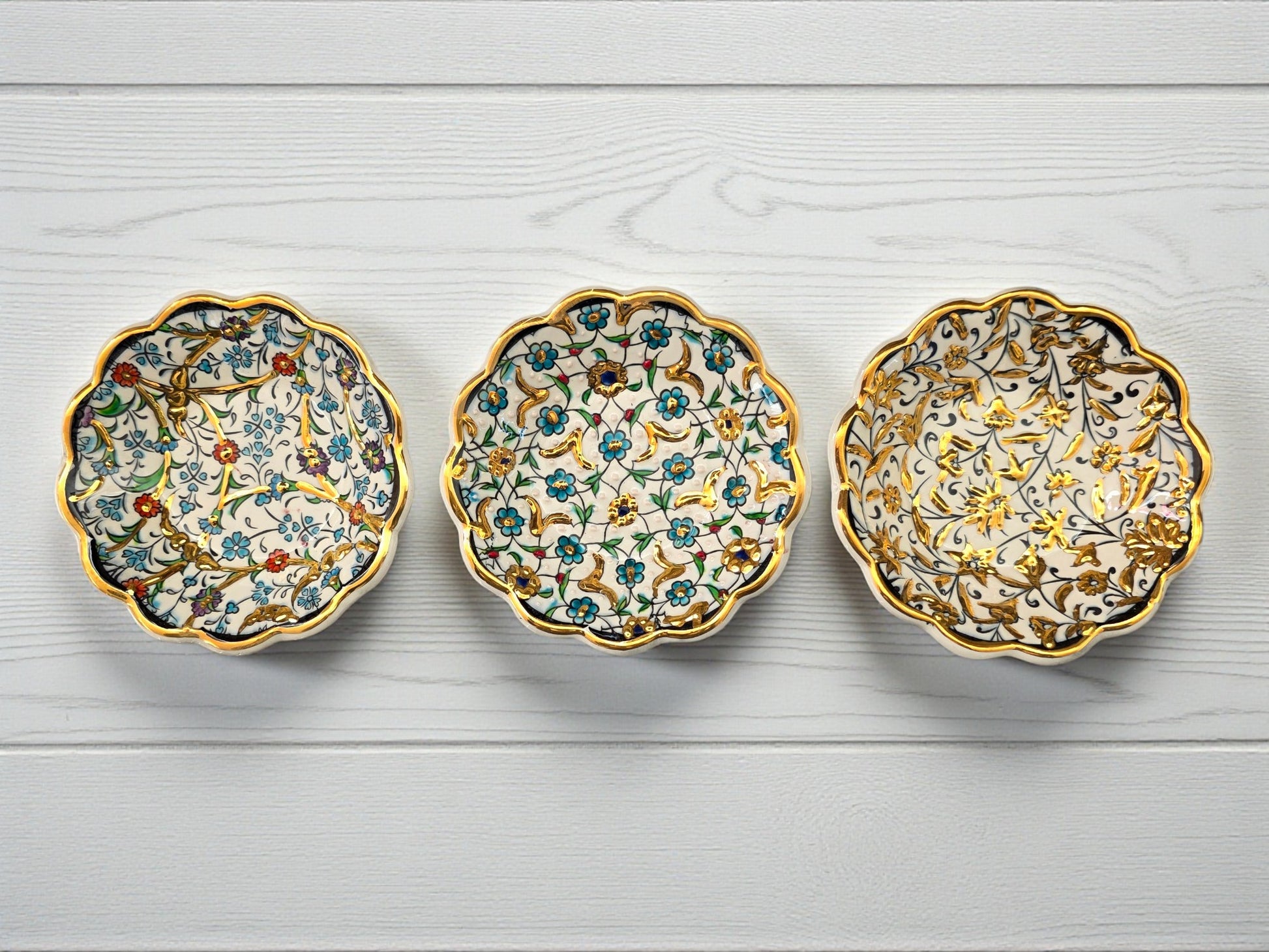 Three decorative ceramic saucers with floral patterns on a light wooden surface