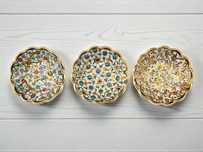 Three decorative ceramic saucers with floral patterns on a light wooden surface