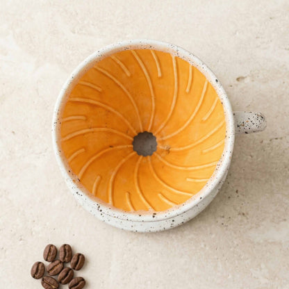 Ceramic mug with a decorative interior pattern on a beige surface with coffee beans.
