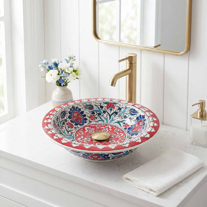 Decorative floral-patterned ceramic sink on a bathroom counter with a gold faucet.