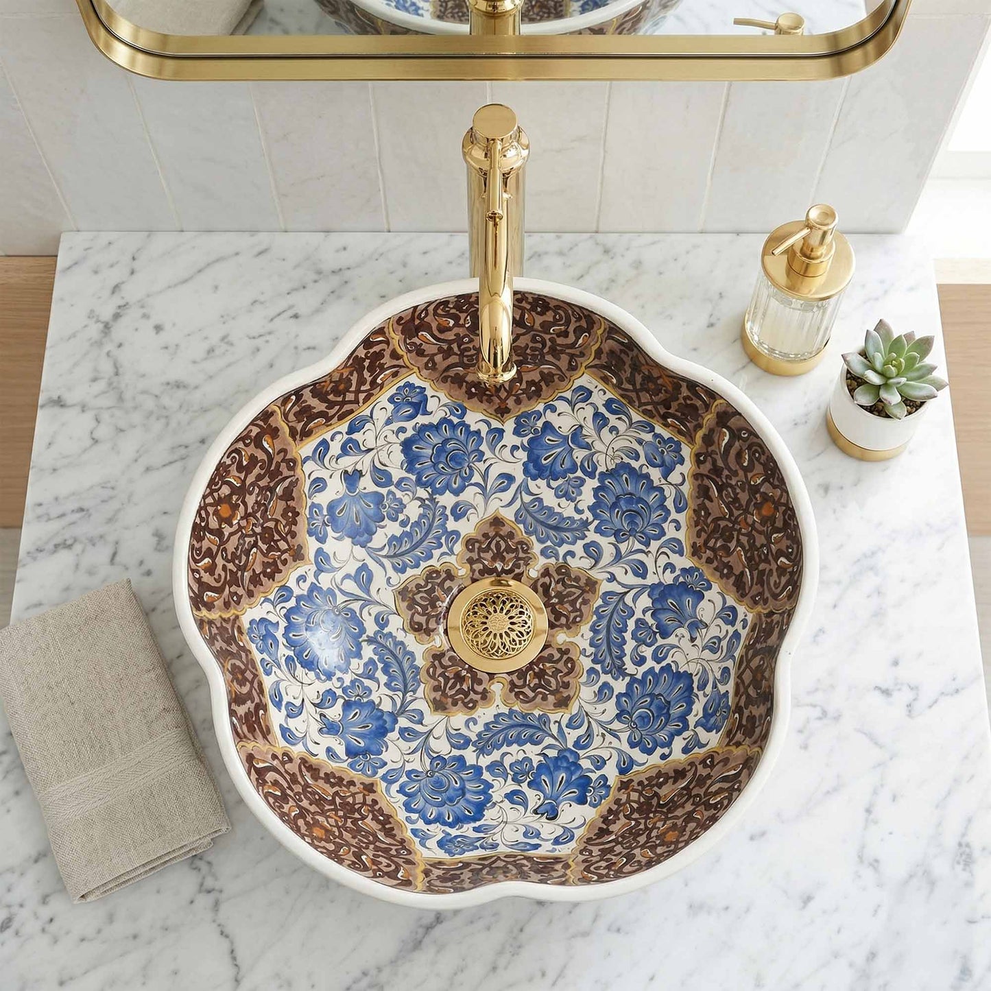 Decorative ceramic sink with floral patterns and gold fixtures on a marble countertop.
