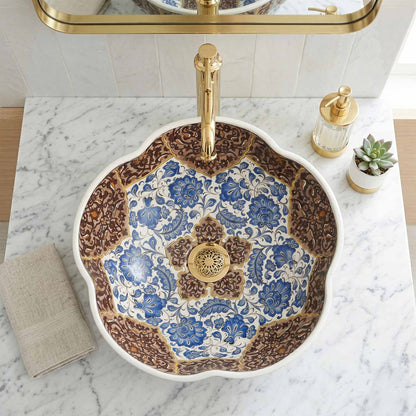 Decorative ceramic sink with floral patterns and gold fixtures on a marble countertop.