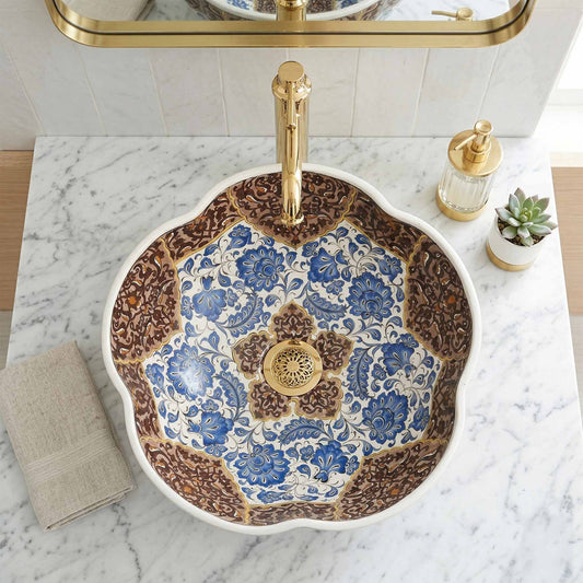 Decorative ceramic sink with floral patterns and gold fixtures on a marble countertop.