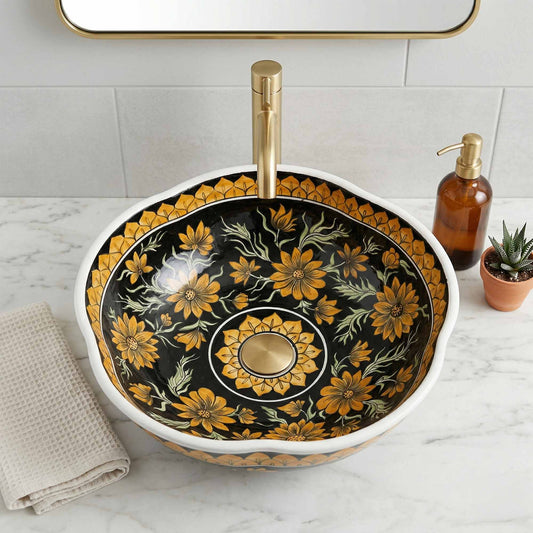 Decorative floral-patterned ceramic sink with gold accents on a marble countertop.