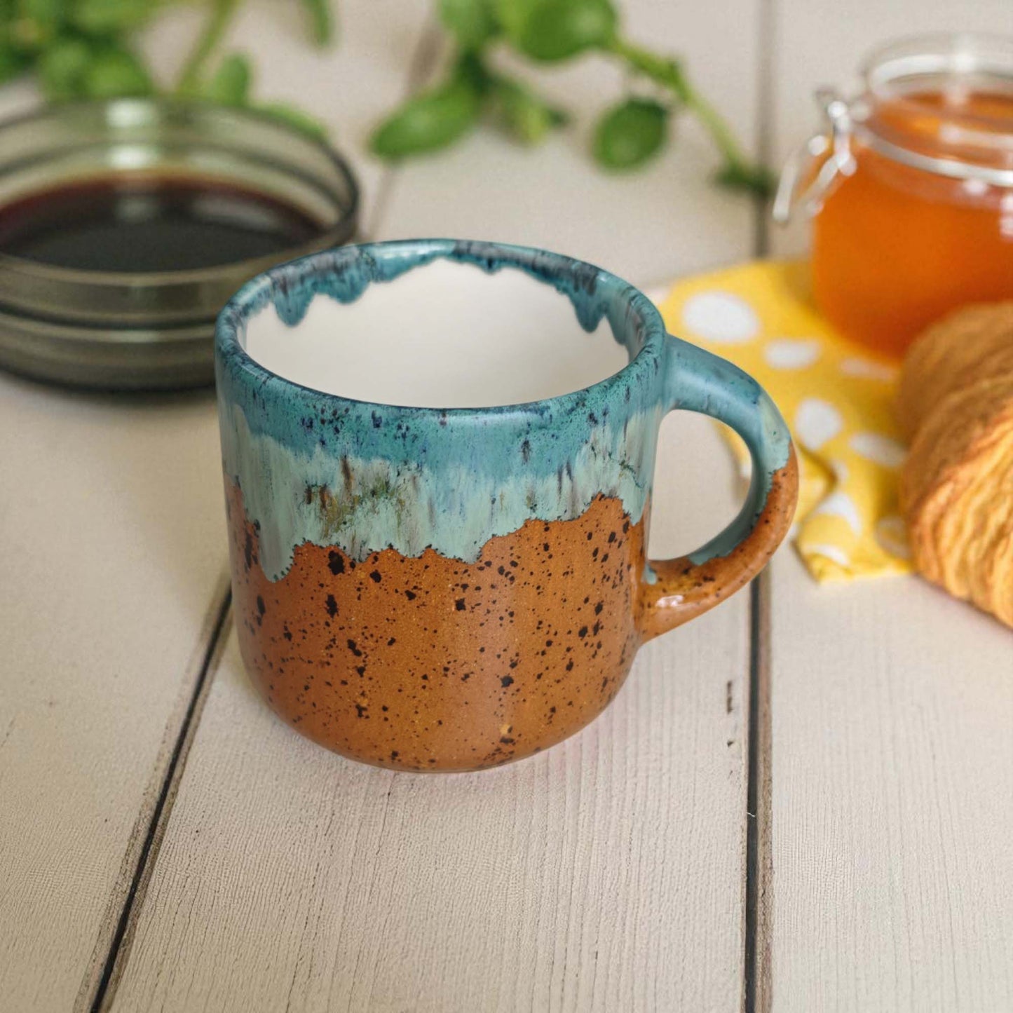 Speckled ceramic mug on a wooden surface with a blurred background