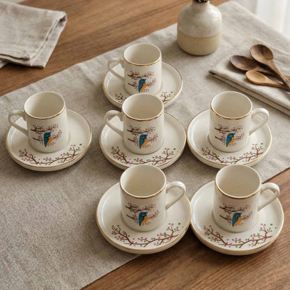Set of porcelain cups and saucers with bird designs on a wooden table.