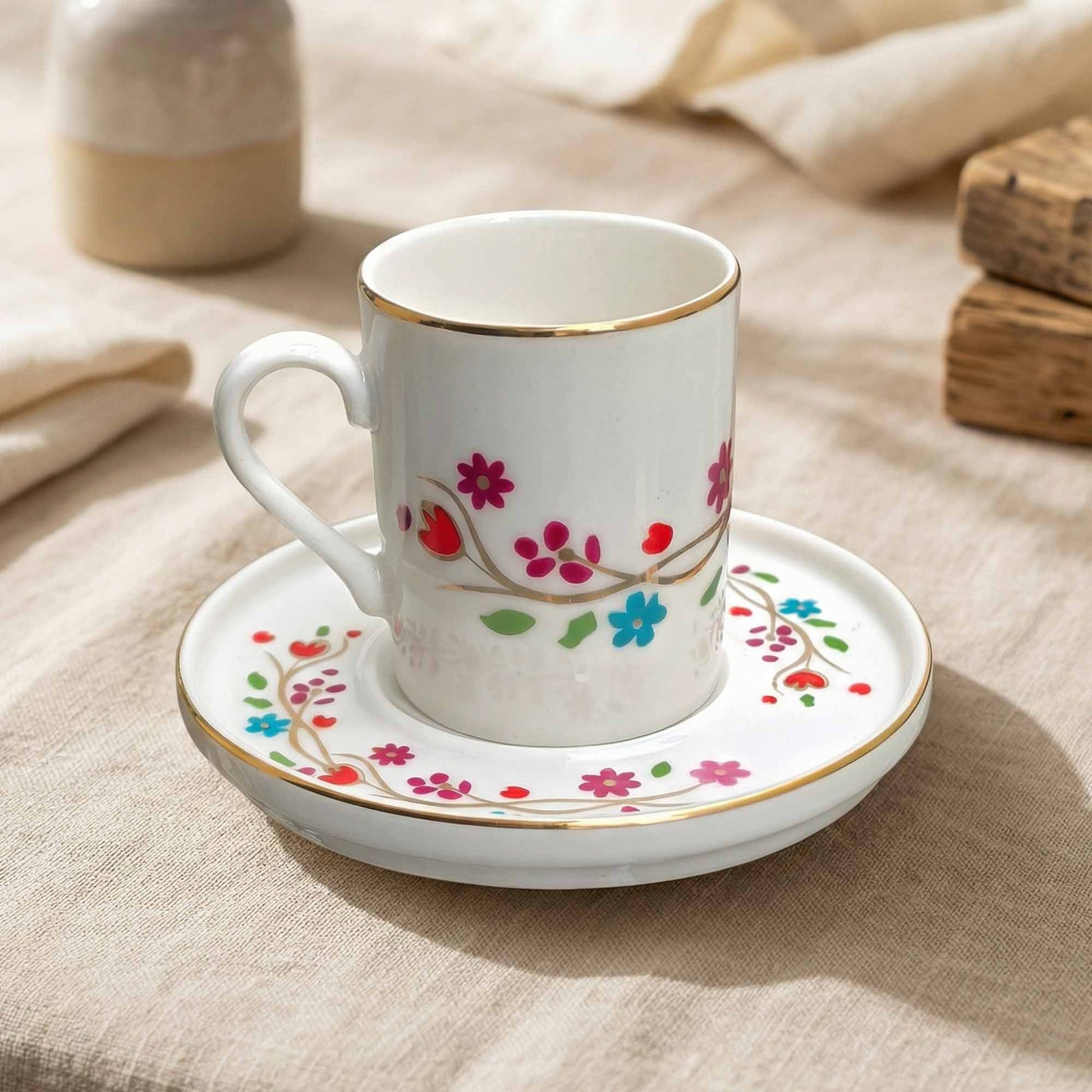 Porcelain cup and saucer with floral design on a beige fabric background
