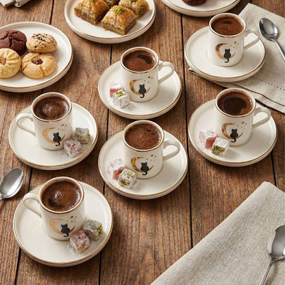 Café au lait cups with saucers on a wooden table with pastries and spoons.