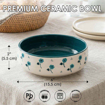 Teal and white ceramic bowl with floral design on a beige surface, showing measurements and safety icons.