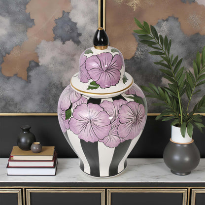 Decorative jar with purple floral design on a table against a textured wall.