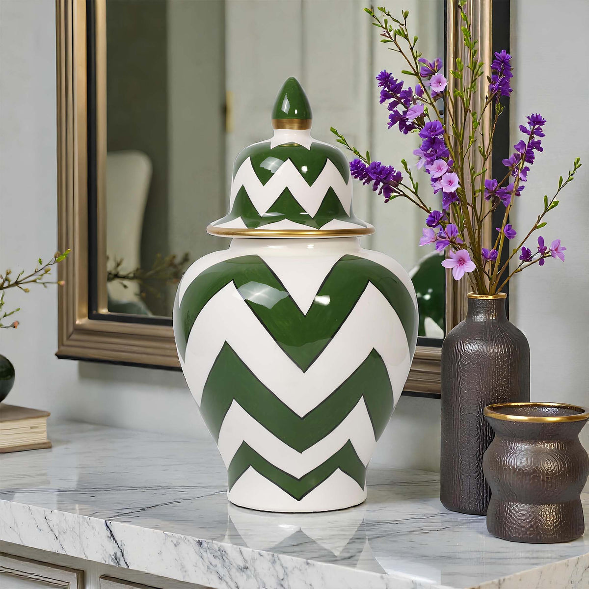 Green and white chevron-patterned jar on a marble surface with decorative vases and flowers in the background.