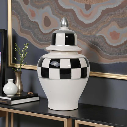Decorative black and white checkered jar on a table with abstract art in the background