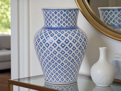 Blue and white patterned vase on a table with a mirror reflecting the vase.