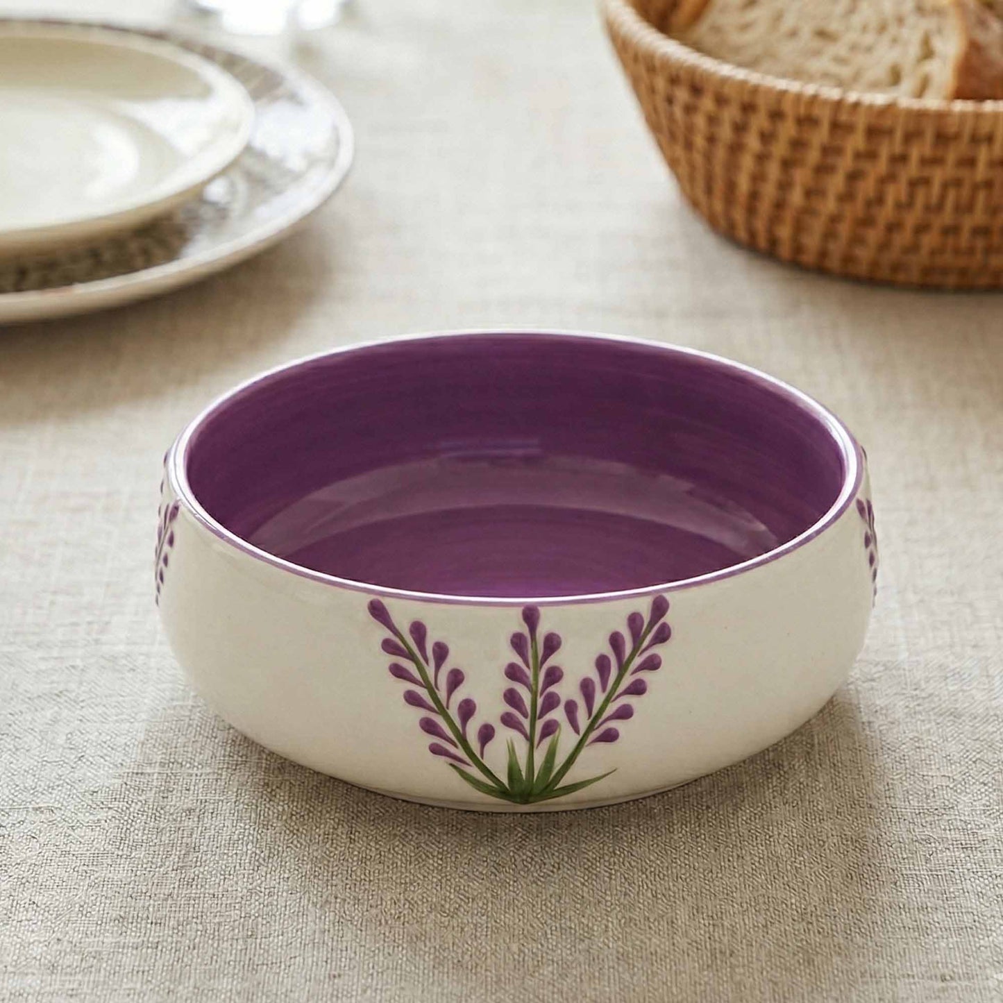 Purple ceramic bowl with floral design on a textured surface