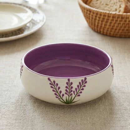 Purple ceramic bowl with floral design on a textured surface
