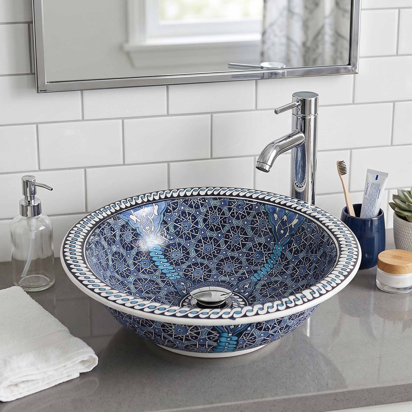 Bathroom sink with decorative blue and white pattern, faucet, and toiletries.