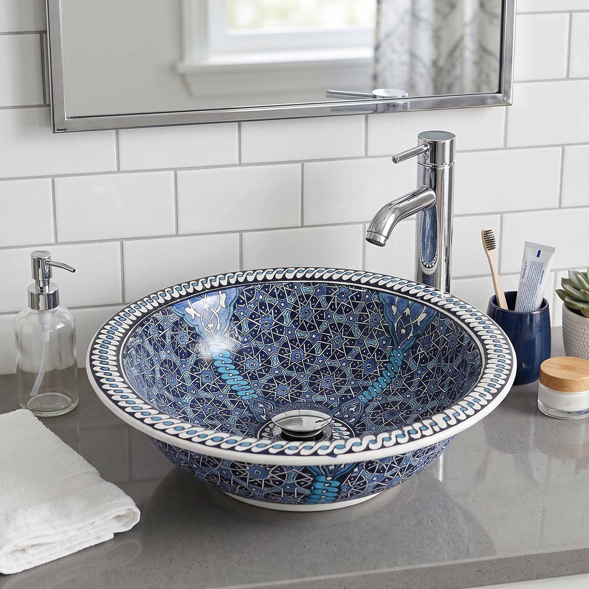 Bathroom sink with decorative blue and white pattern, faucet, and toiletries.